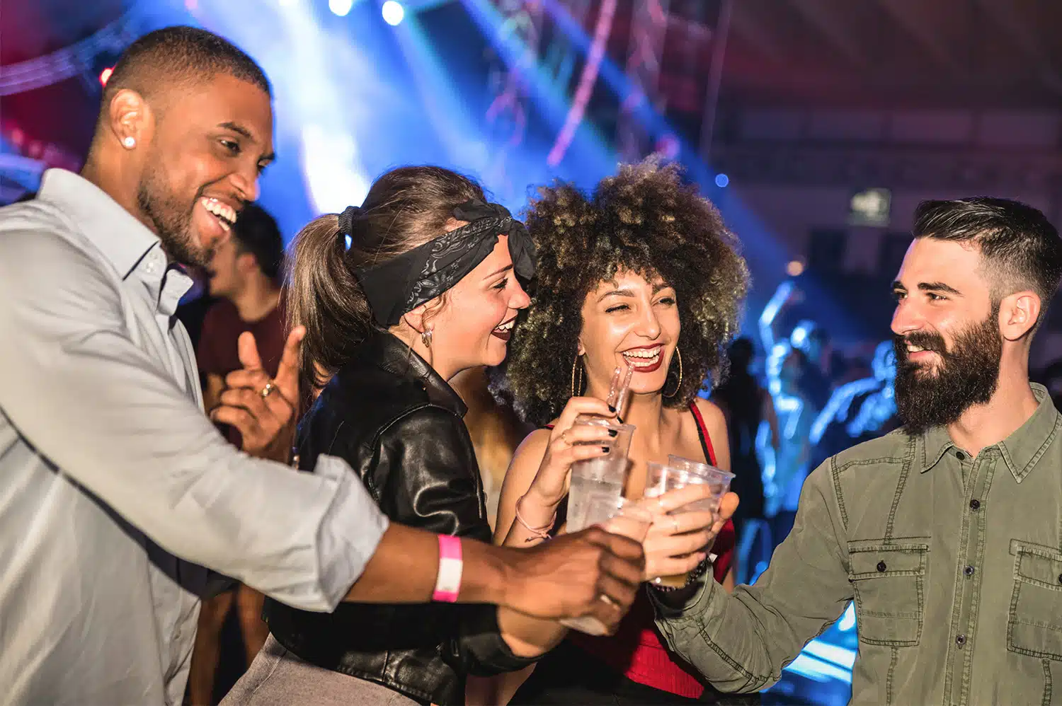 People cheers-ing drinks in a club, with their party bus rental waiting for them outside.