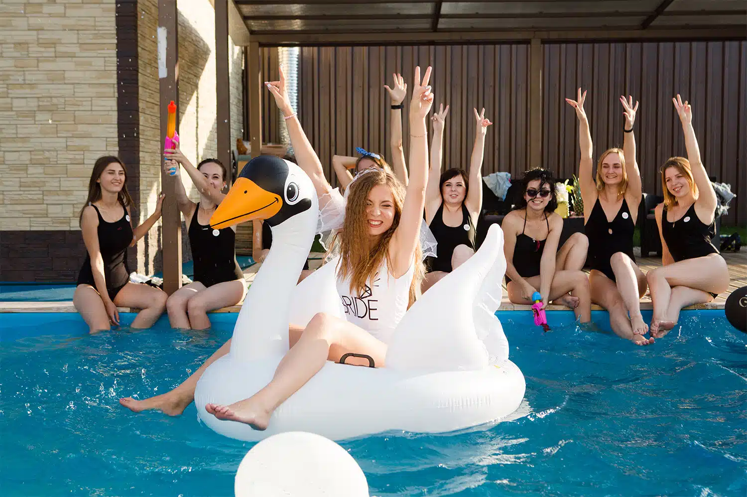 A bachelorette party celebrating in a pool.